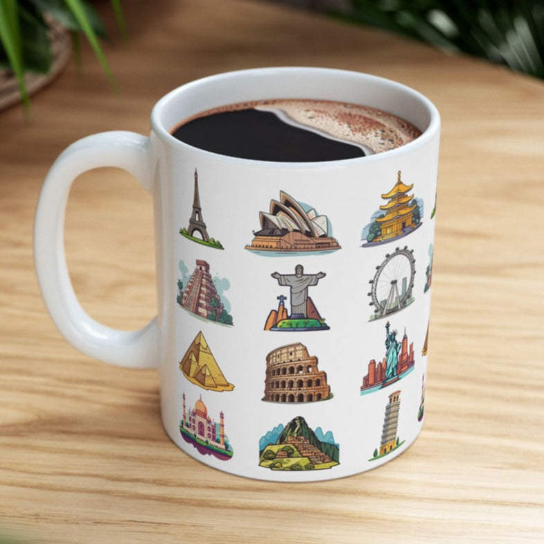 White ceramic coffee mug featuring famous world travel landmarks, resting on a rustic wooden table surrounded by lush green plant decor