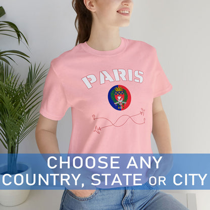 White woman wearing a light pink cotton T-shirt featuring the word 'Paris' and its rounded flag