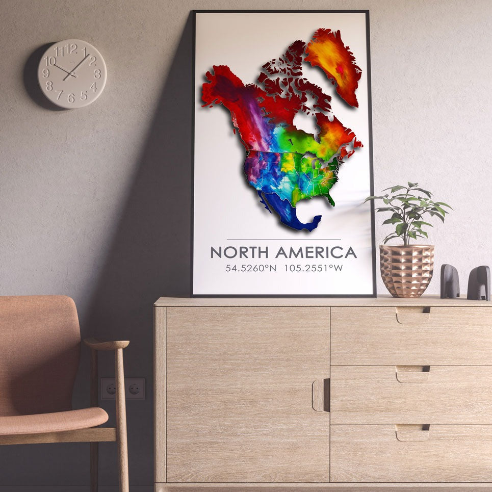 Black-framed colorful North America map poster on a light beige cabinet against a light pink wall with surrounding decor