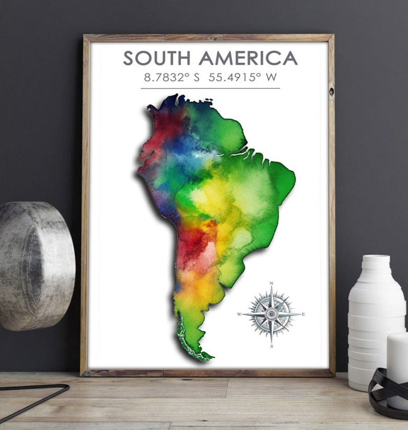Wood-framed poster featuring a colorful map of South America, displayed against a sophisticated dark gray wall on a rich brown table, surrounded by decorative elements