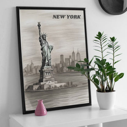 Black-framed poster featuring a pencil drawing of the Statue of Liberty in New York, elegantly displayed against a clean white wall, on a sleek white table, next to a plant and other decoration