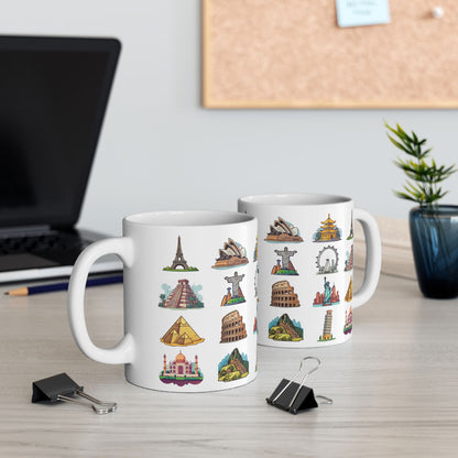 two white ceramic coffee mugs featuring famous world travel landmarks, on a light gray office table next to a computer and other decoration 