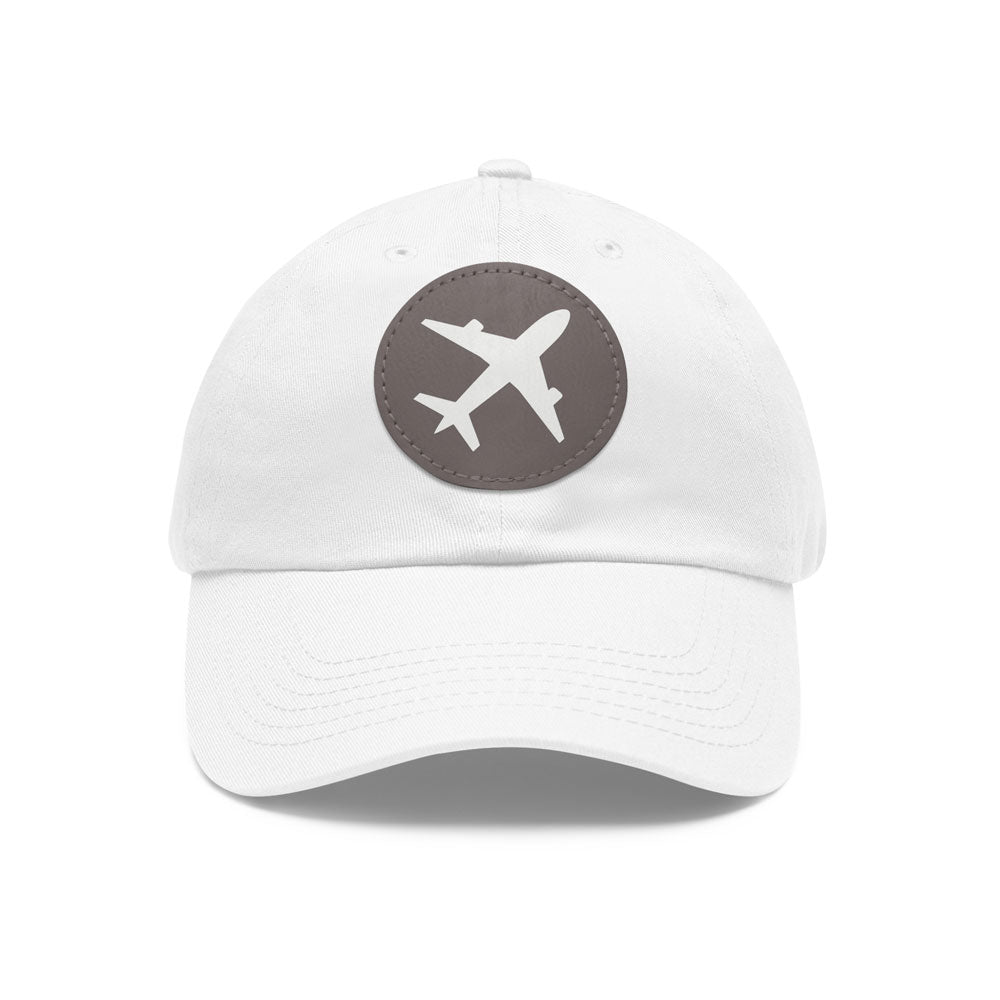 Stylish white twill cotton baseball cap with a round gray leather patch showcasing an airplane emblem, on a white background
